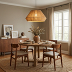 This Clérachic pendant hangs above a round wood dining table with woven-back chairs and a jute rug underfoot.
