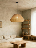 In a living room corner, this Clérachic pendant hangs near open wood shelving, a woven sofa and a low wood coffee table.