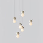 A cluster of pale sphere pendants from this Clérachic collection hangs at staggered heights against a plain light-grey backdrop.