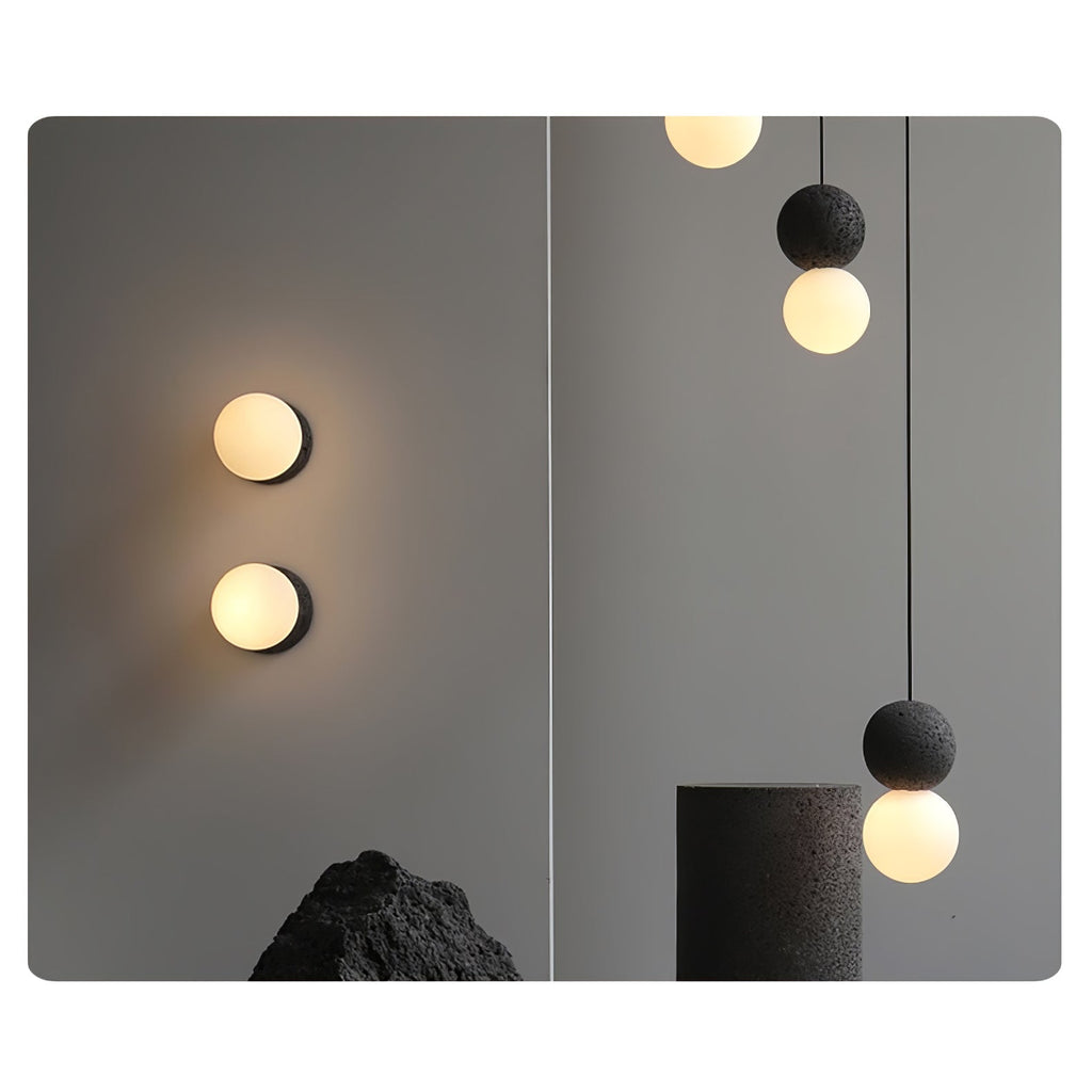 This Clérachic pendant hangs near a stone plinth, beside two round wall lights glowing on a charcoal-grey wall.