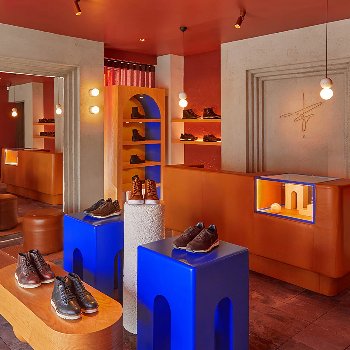 This Clérachic pendant lights a shoe display with cobalt-blue plinths in a warm, orange-toned boutique.