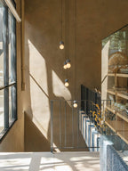 This Clérachic pendant cluster hangs above a staircase landing, its dark spheres catching afternoon light against a warm wood wall.