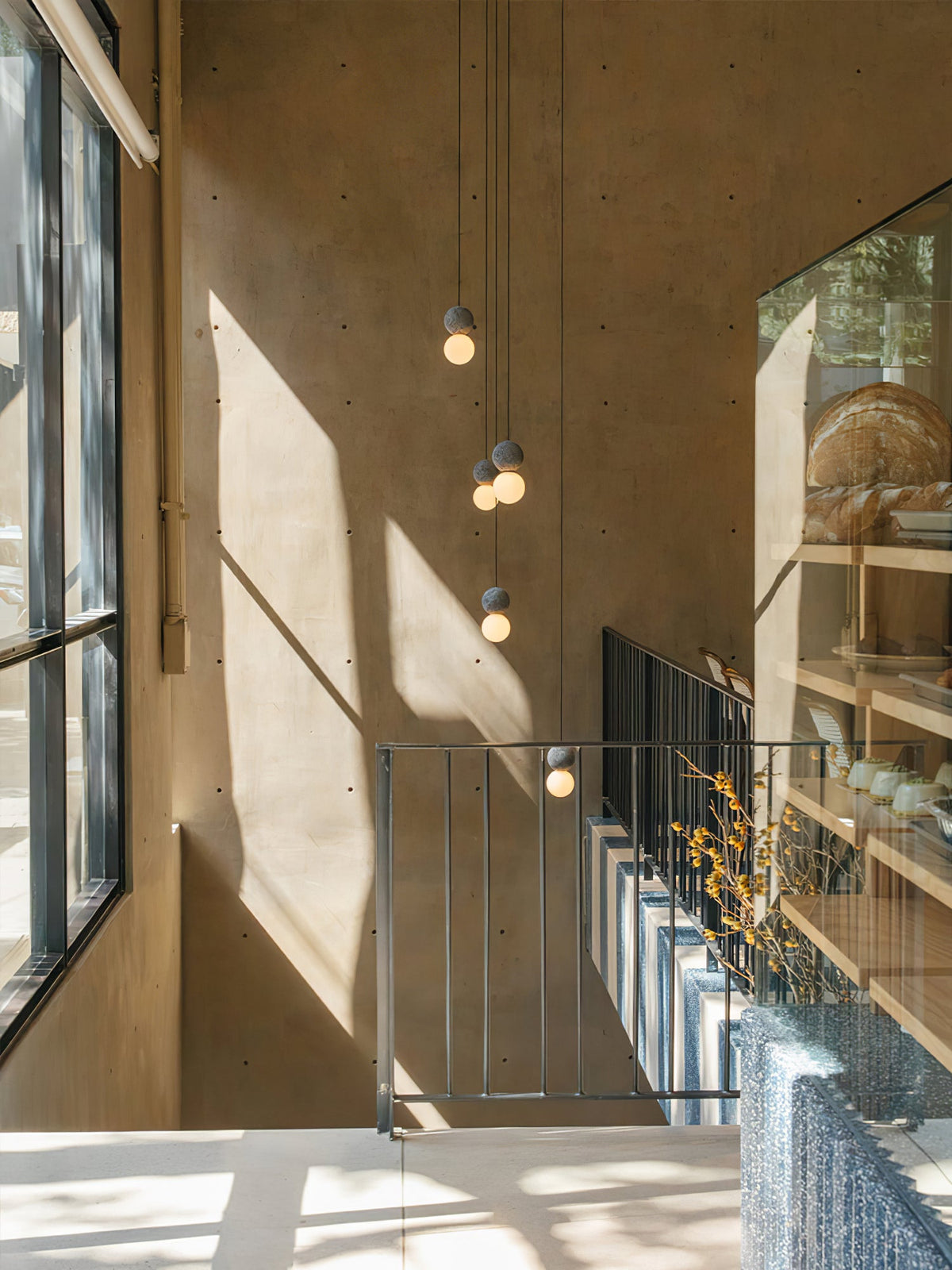 This Clérachic pendant cluster hangs above a staircase landing, its dark spheres catching afternoon light against a warm wood wall.