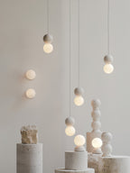Clérachic pendants of different heights hang above a row of stone plinths topped with a stacked stone finial.