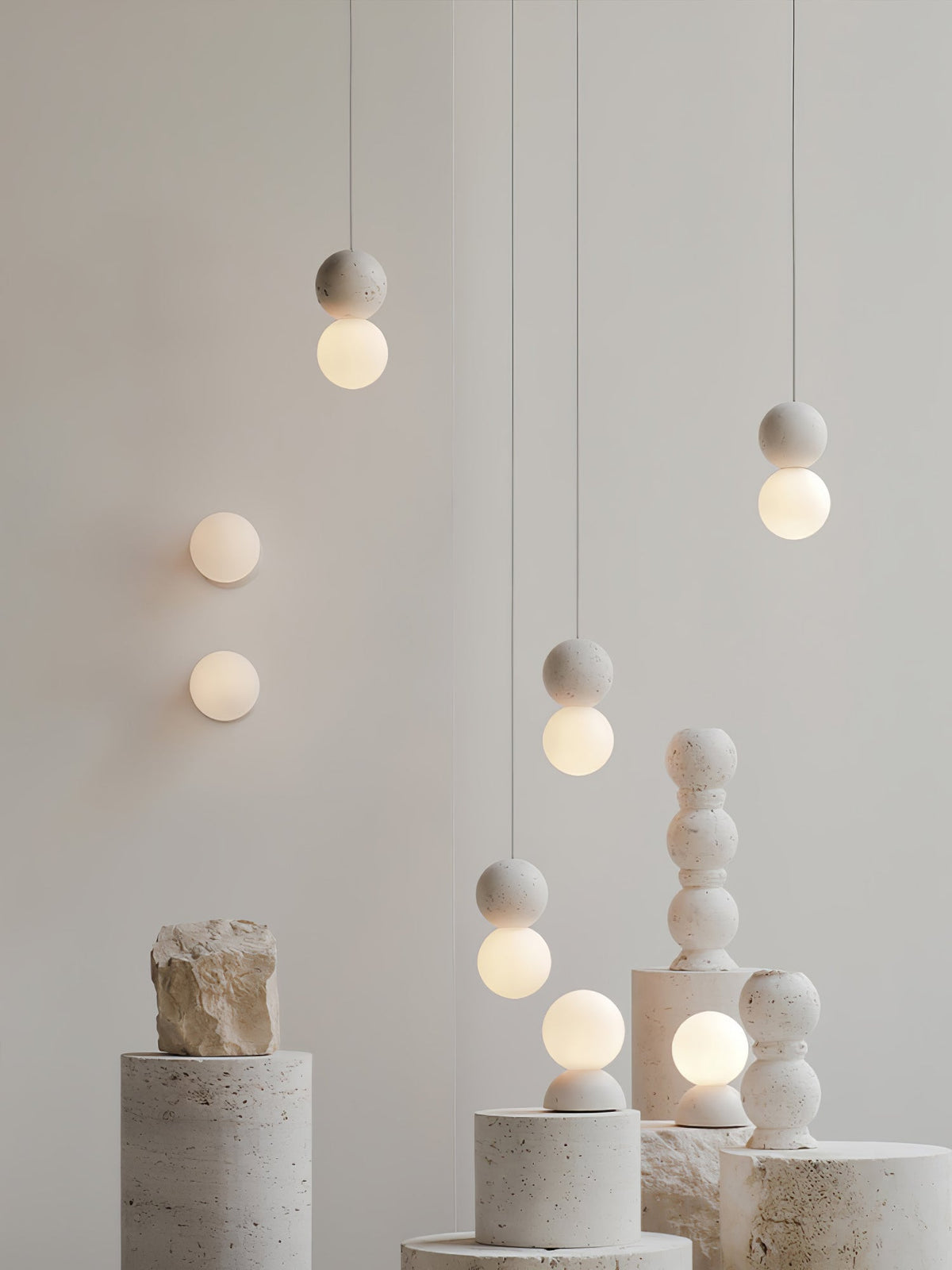 Clérachic pendants of different heights hang above a row of stone plinths topped with a stacked stone finial.