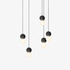 A cluster of dark sphere pendants with opal glass globes from this Clérachic collection hangs against a plain white backdrop.