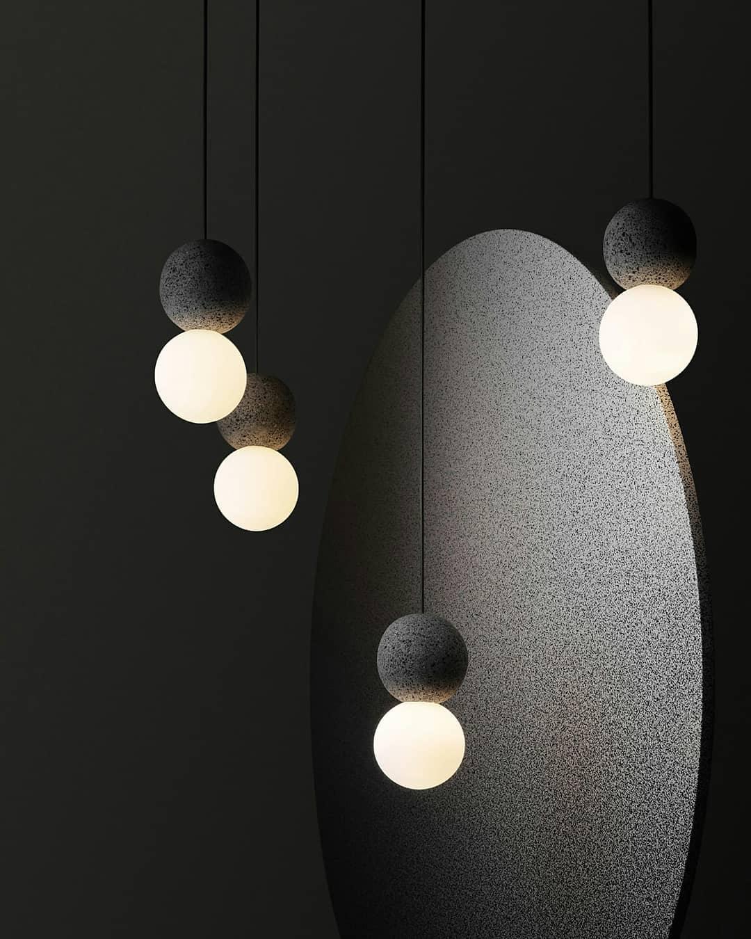 Multiple dark pendants from this Clérachic collection hang beside a large oval sculptural form on a near-black backdrop.