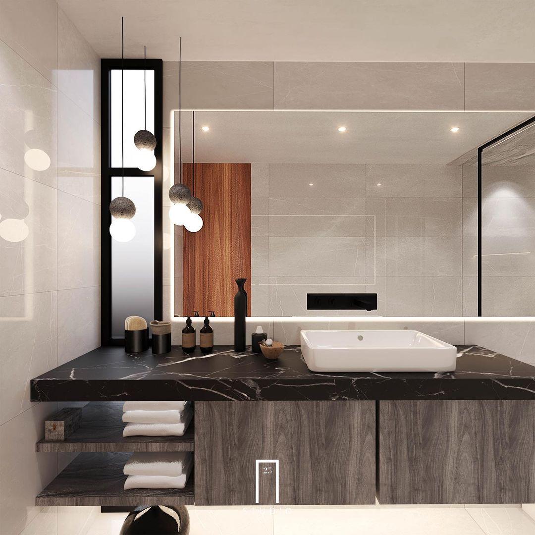 Two Clérachic pendants of different drop lengths hang above a black marble vanity with a mirrored wall behind.