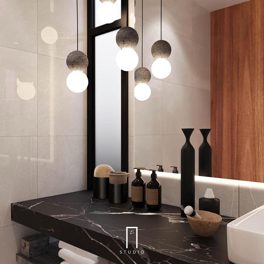 A cluster of Clérachic pendants hangs above a black marble bathroom counter, reflected in the mirror behind the vanity.