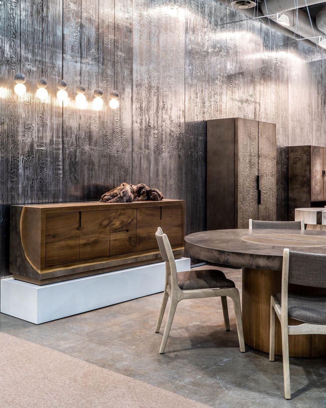 A row of Clérachic pendants glows above a rustic wood cabinet, in a dining space with a round table and chairs.
