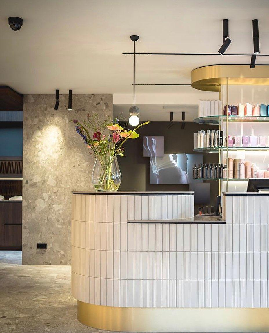 This Clérachic pendant hangs above a curved reception counter, its dark sphere and glass globe set against a rough stone wall.