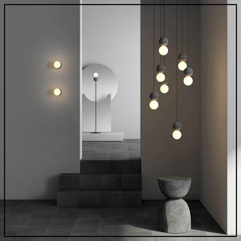 A vertical string of Clérachic pendants lights a staged room with stairs, a floor lamp and wall sconces nearby.