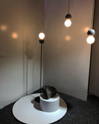 Clérachic pendants surround a round white side table holding a small rock, their light casting patterned shadows on the wall.