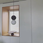 Two Clérachic pendants of different heights hang inside a wood-framed nook, above a small stone dish.