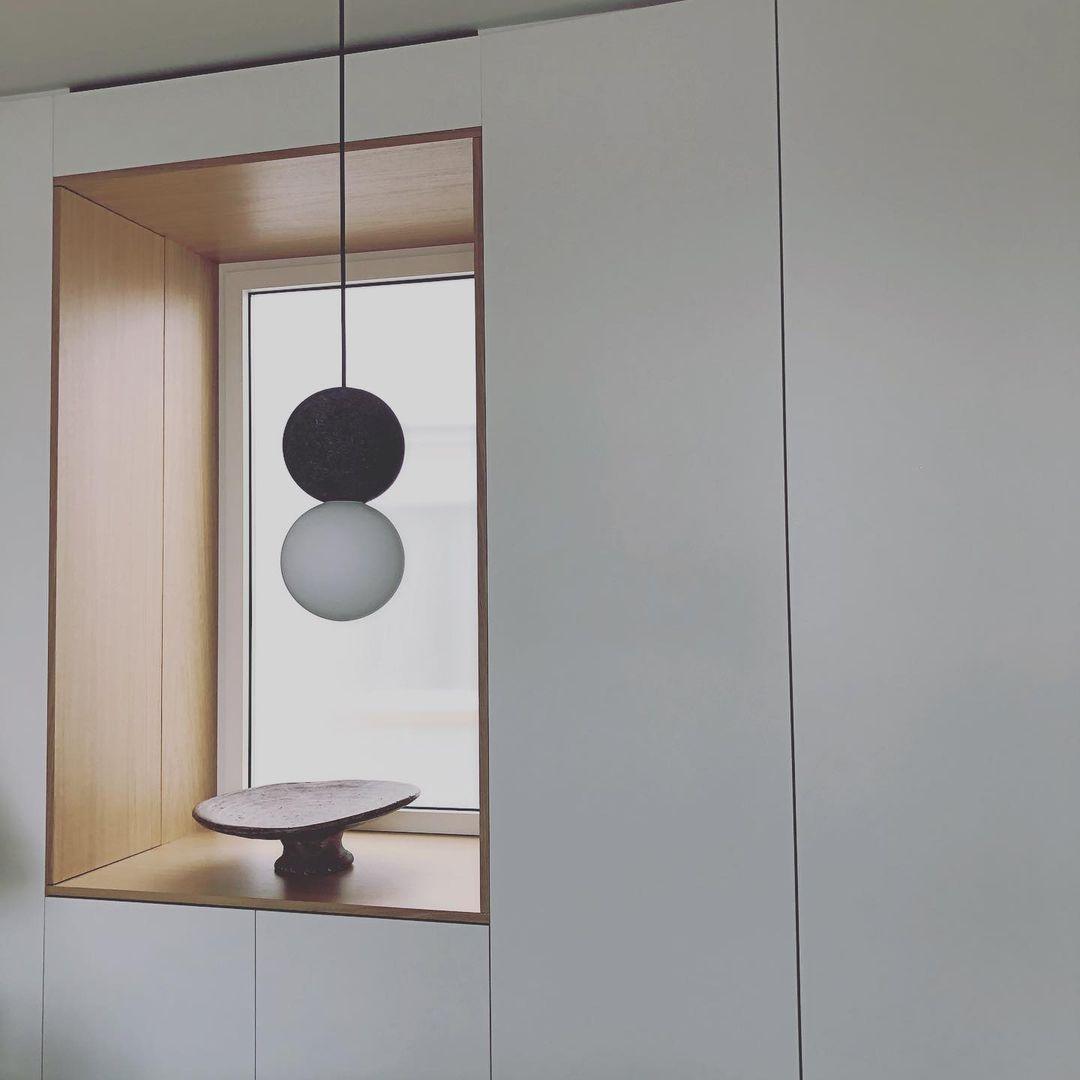 Two Clérachic pendants of different heights hang inside a wood-framed nook, above a small stone dish.