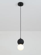 This Clérachic pendant, a dark textured sphere above an opal glass globe, drops from a plain white ceiling on a black cord.
