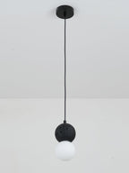 A single Clérachic pendant with a dark textured sphere and an opal glass globe drops from a plain white ceiling.