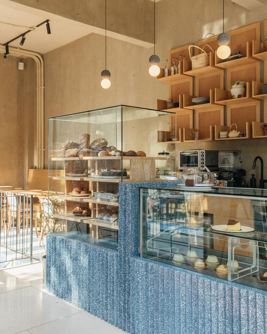 Pendants from this Clérachic collection hang above a bakery counter, lighting glass display cases of pastries.