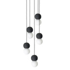 A five-light cluster of Clérachic pendants hangs together, dark and grey stone spheres paired with opal glass globes.