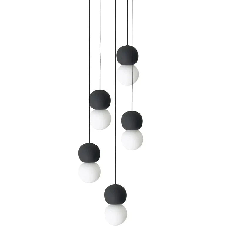 A five-light cluster of Clérachic pendants hangs together, dark and grey stone spheres paired with opal glass globes.