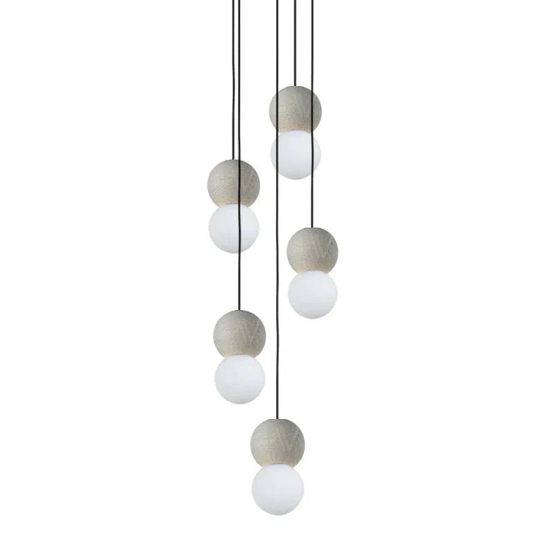 Several pale grey and white sphere pendants from this Clérachic collection hang together at different heights on thin black cords.