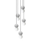 Pale grey and white sphere pendants from this Clérachic collection hang at staggered heights, clustered together on thin black cords.