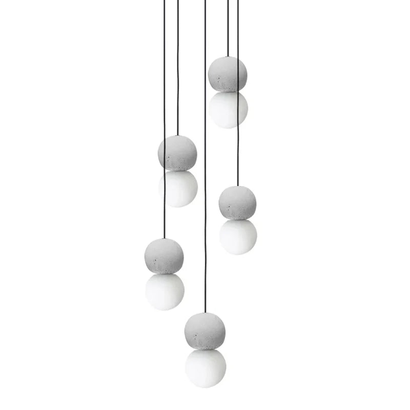 Pale grey and white sphere pendants from this Clérachic collection hang at staggered heights, clustered together on thin black cords.