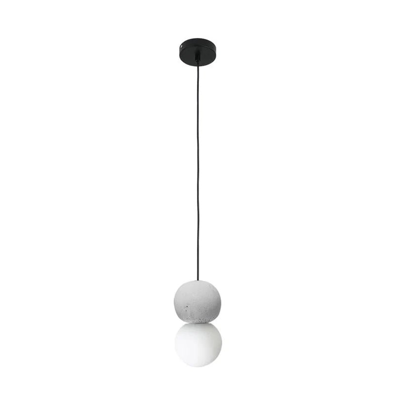 This Clérachic pendant, a grey stone-textured sphere above an opal glass globe, hangs from a black ceiling canopy on white.