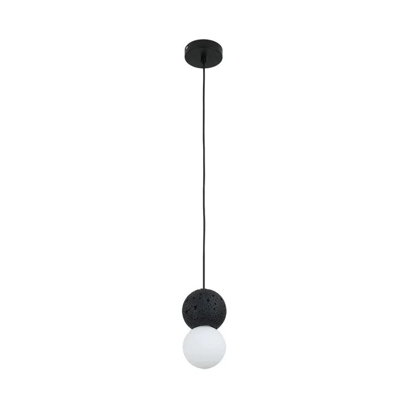 This Clérachic pendant pairs a black stone-textured sphere with an opal glass globe, hanging from a round black canopy.