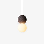This Clérachic pendant, a dark stone-textured sphere fading to black above an opal glass globe, hangs against a plain white background.