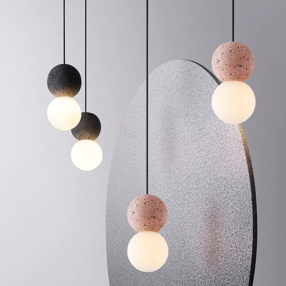 Clérachic pendants in dark and dusty-pink stone hang beside a large speckled grey sculptural panel.