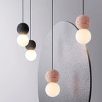 Clérachic pendants in dark and dusty-pink stone hang beside a large speckled grey sculptural panel.