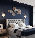 This Clérachic pendant hangs in a navy-painted bedroom, near a cluster of wood slice wall decor above a tufted headboard.