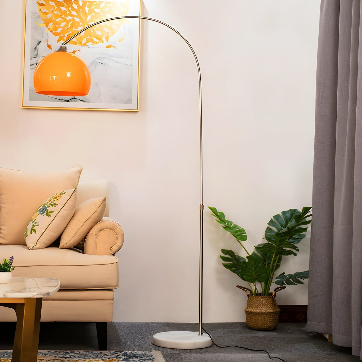 In a living room, a Clérachic arc floor lamp with an orange dome shade curves over a cream armchair beside a potted plant.