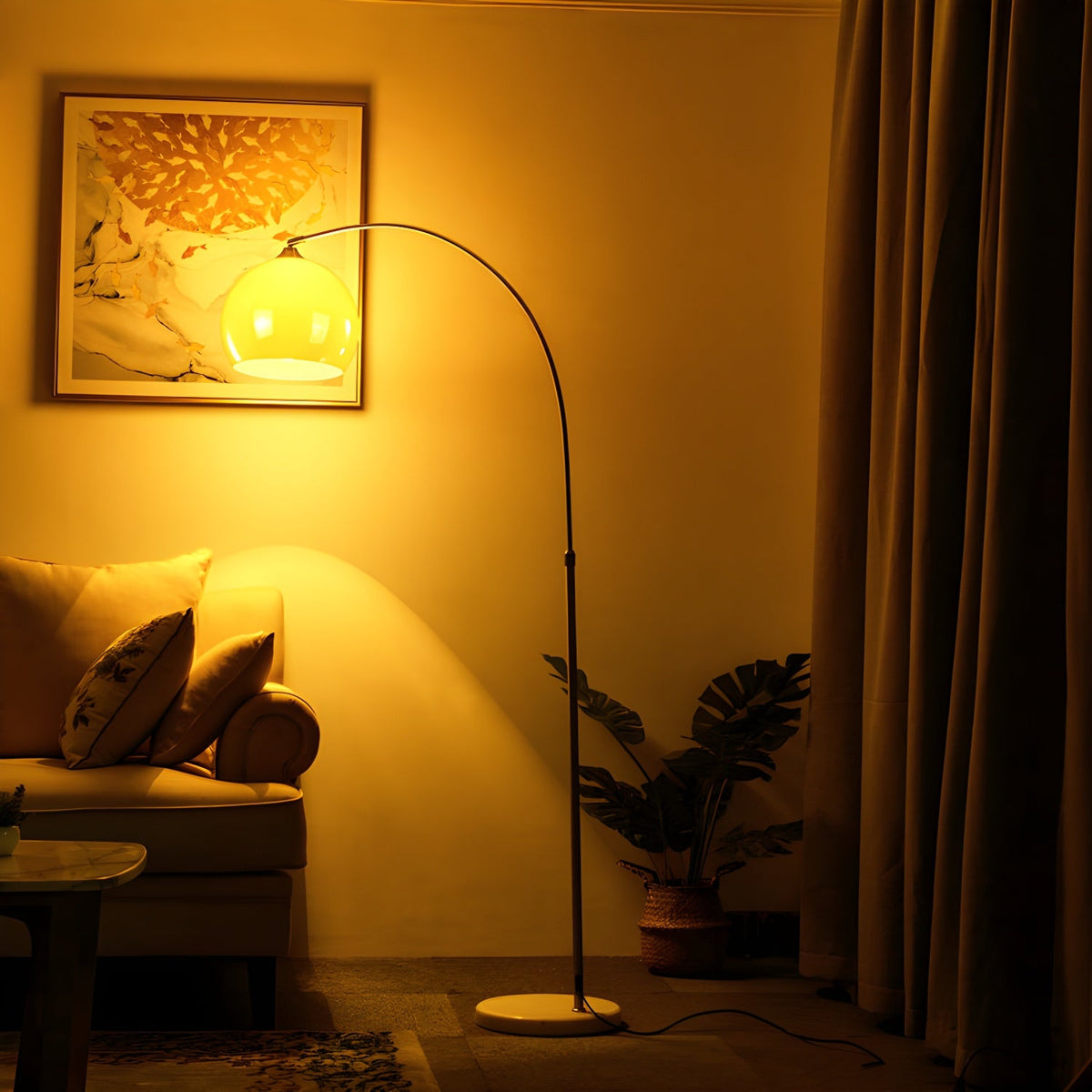 Glowing warm yellow, a Clérachic arc floor lamp curves over a sofa in a room with mustard curtains and a framed print.