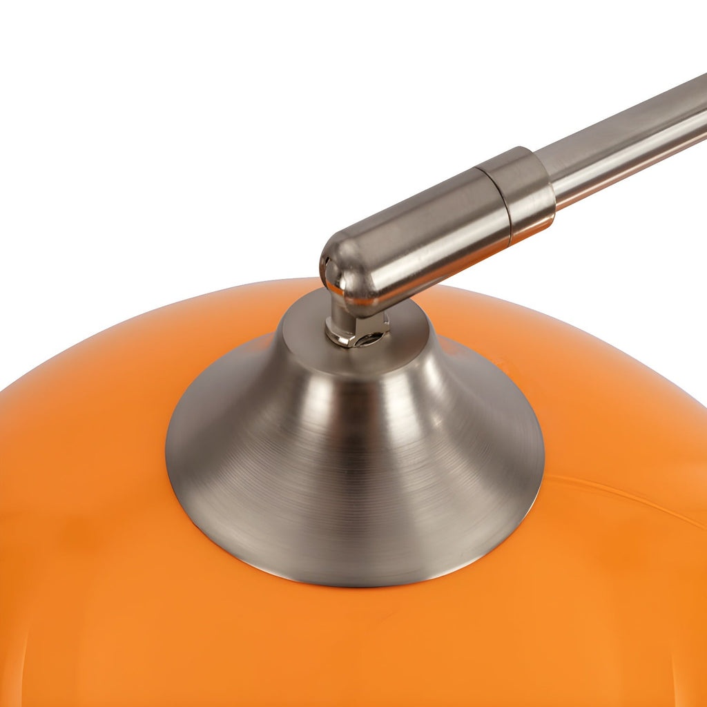 Close-up of the brushed nickel joint where a Clérachic arc floor lamp's arm meets its glossy orange dome shade.