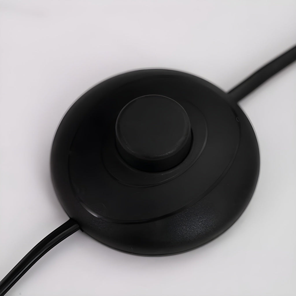 Close-up of the round black inline foot switch on the power cord of a Clérachic arc floor lamp.