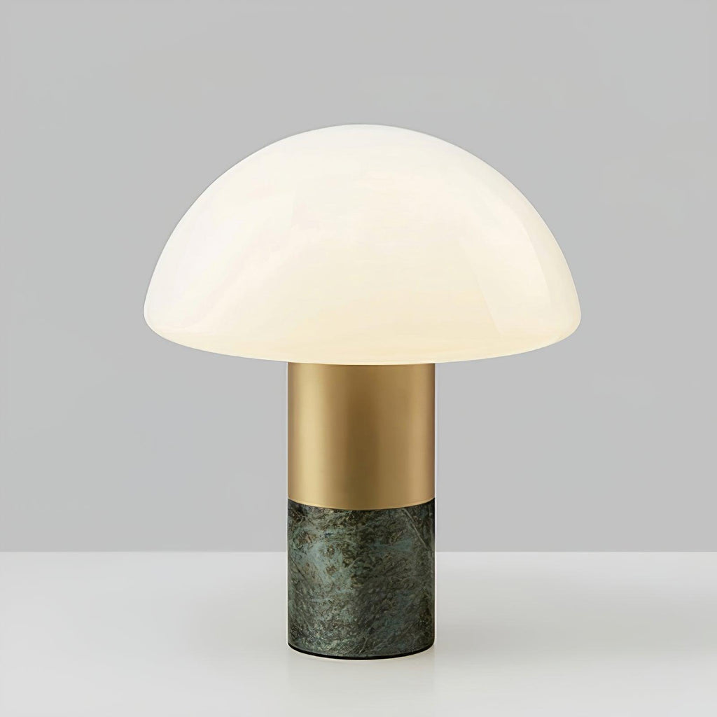 Studio shot of a Clérachic domed glass table lamp with a green marble base, centred against a grey gradient backdrop.