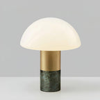 Studio shot of a Clérachic domed glass table lamp with a green marble base, centred against a grey gradient backdrop.