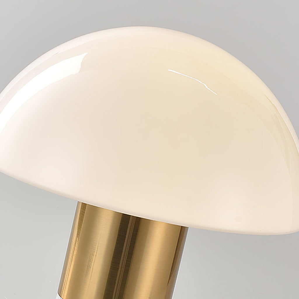 A closer crop shows the curve of a Clérachic domed table lamp's glass shade against its polished gold neck.