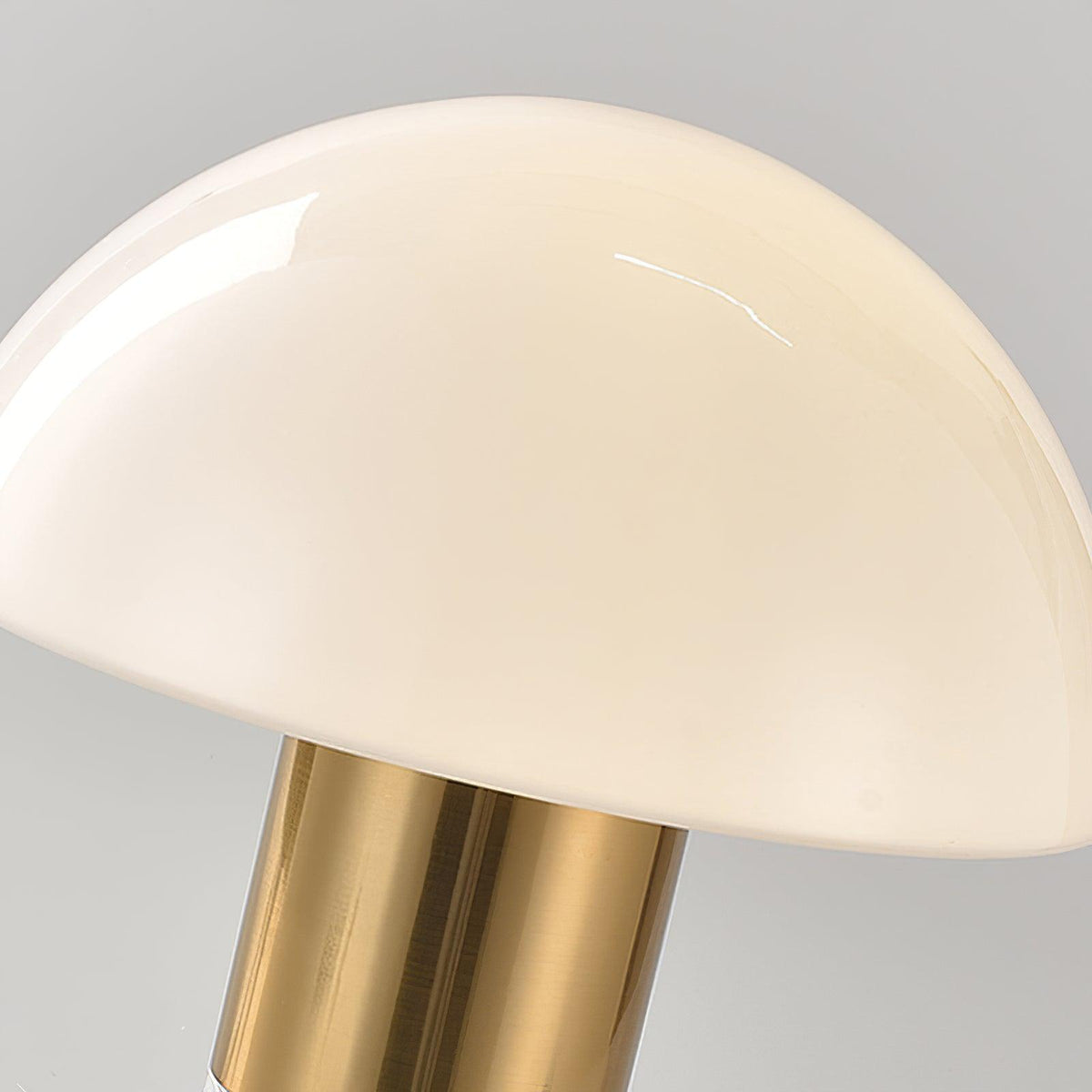 A closer crop shows the curve of a Clérachic domed table lamp's glass shade against its polished gold neck.