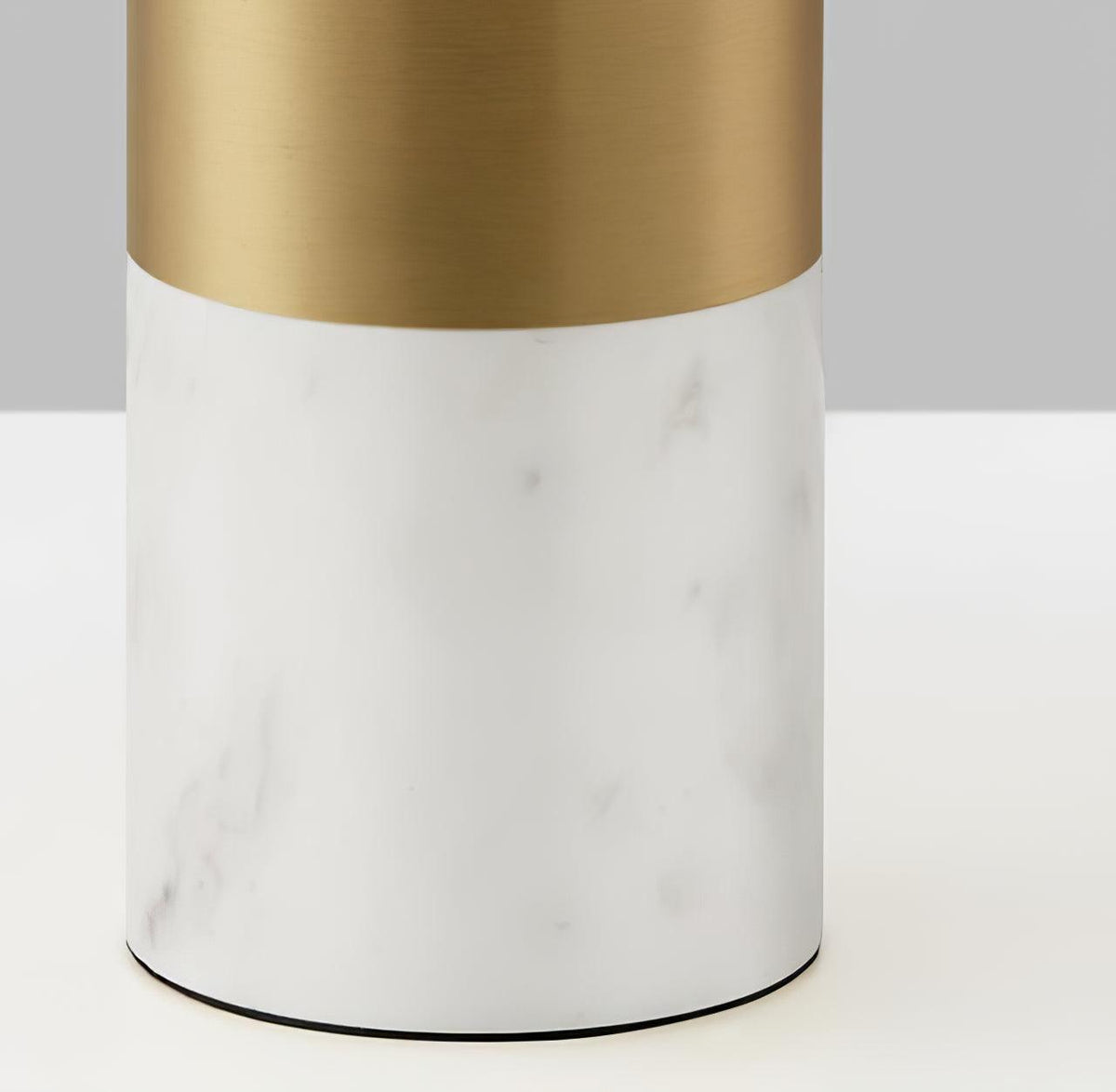 Close-up of the white marble base and brushed gold neck of a Clérachic domed table lamp, its shade out of frame.