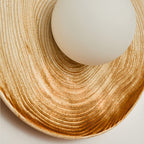 Close-up of the opal glass globe set into the ridged ceramic disc of a Clérachic wall sconce, its grooves radiating outward.