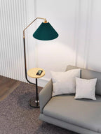 Clérachic floor lamp in the same panelled room, green shade lit above a wood tray holding a phone, shown from a slightly wider angle.