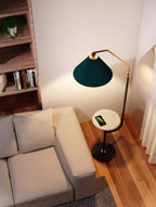 Clérachic floor lamp against a bookshelf with potted plants on top, green pleated shade lit above a marble tray holding a phone.