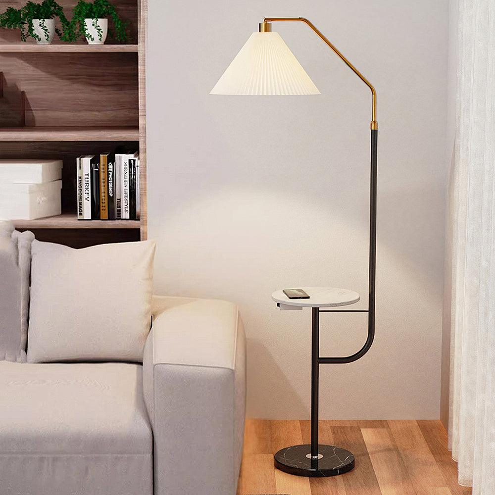 Clérachic floor lamp against the same bookshelf backdrop, cream shade lit above a marble-topped tray holding a phone.