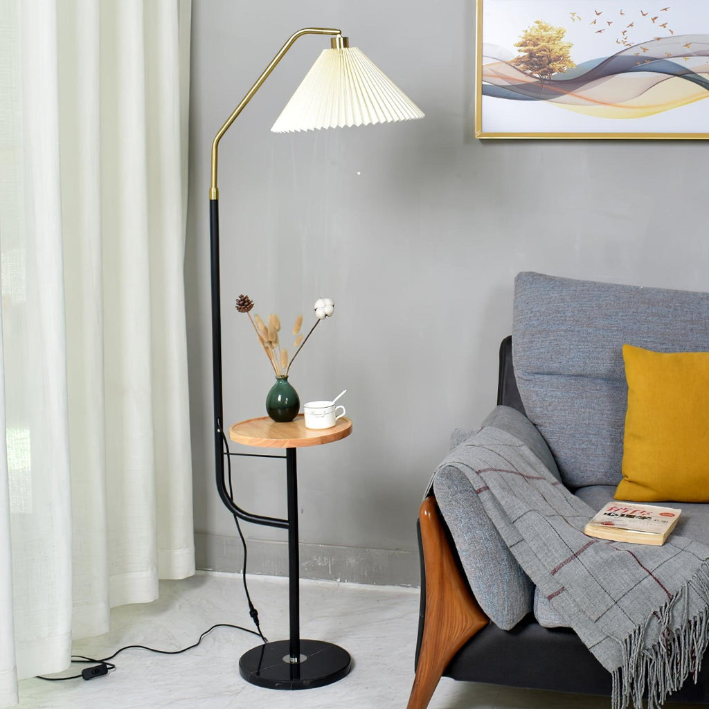 Clérachic floor lamp beside a grey armchair with a mustard cushion and folded throw, cream shade lit above a white tray with a mini vase and cup.