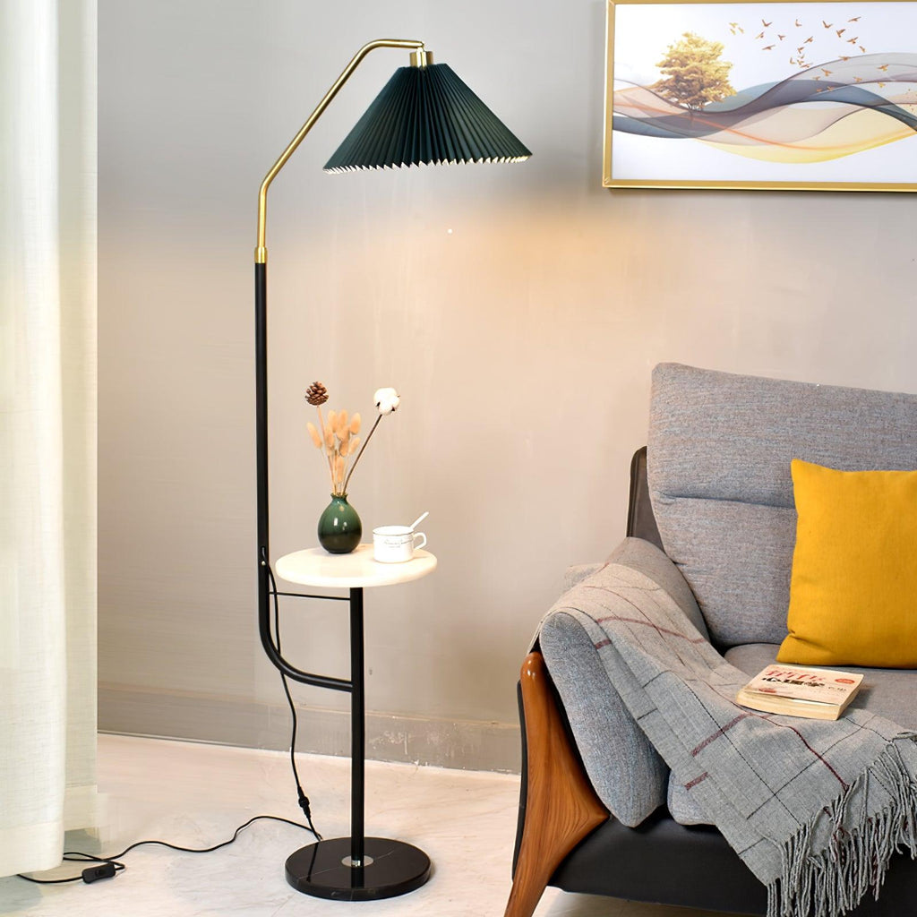 Clérachic floor lamp beside a grey armchair with a mustard cushion and folded throw, green shade lit above a white tray holding a mini vase and cup.