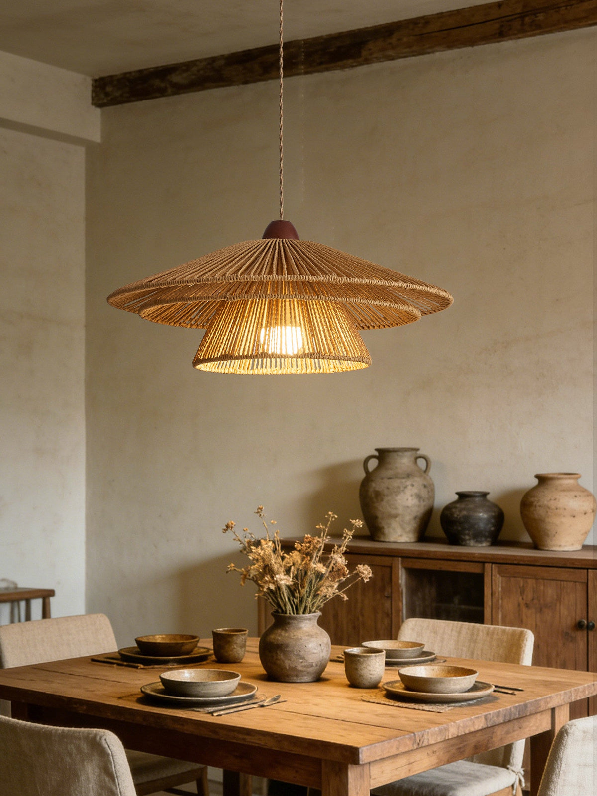 Ceramic dishes and dried flowers dress a rustic wood table beneath this Clérachic pendant's warm glow.