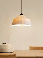 Above a wood table with a woven basket stool nearby, this Clérachic pendant's beige cone shade glows warm.